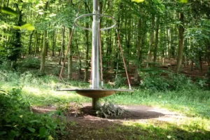Rundes Hängesitz-Karussell an einem Mast im Wald auf dem Spielplatzgelände